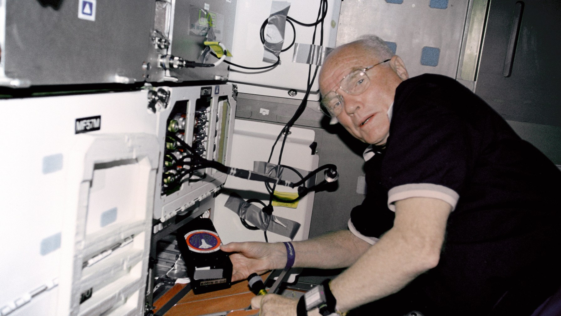 John Glenn working on an experiment on the middeck of Space Shuttle Discovery during STS-95