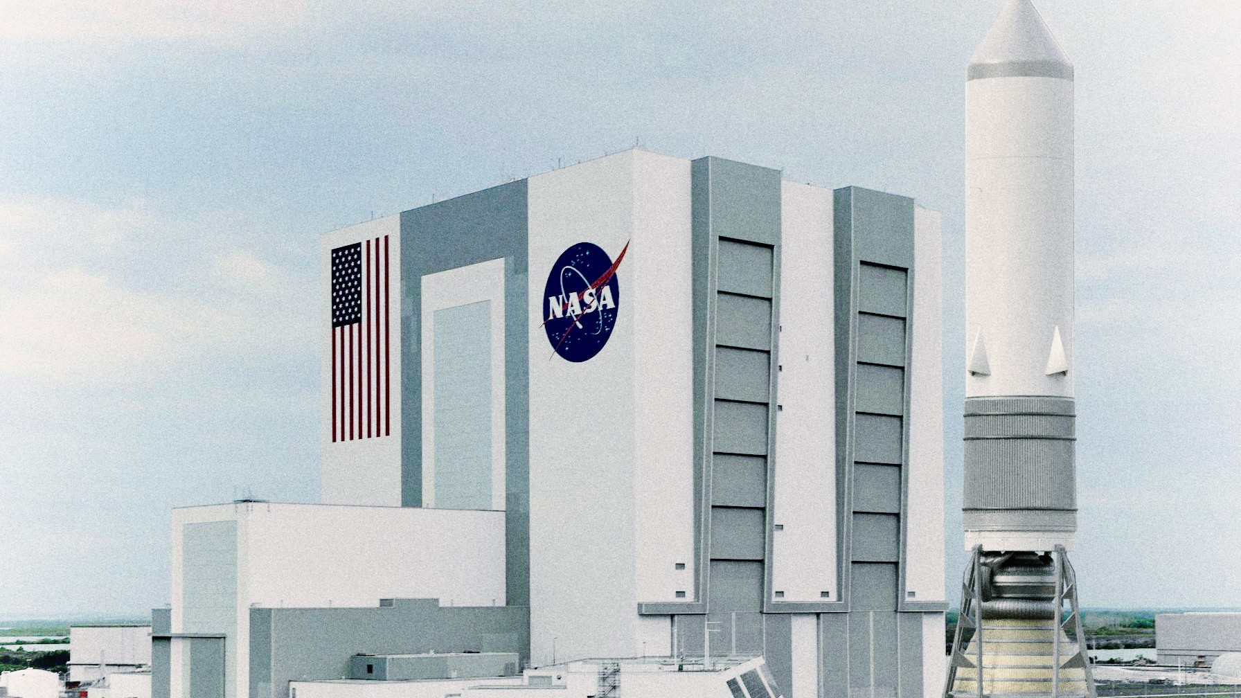 Composite visualisation of the unbuilt Sea Dragon rocket beside NASA's Vehicle Assembly Building for scale
